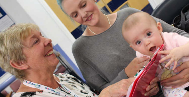 A Healthwatch Dudley volunteer talks to a woman and her baby in a waiting room