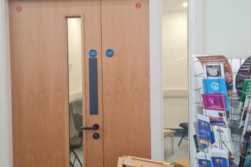 Sign above door that says "Information Hub Parents, Carers & Staff. A stand with information leaflets.