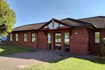 Photo of castle meadows surgery. Single story building with grass in front and blue skies above.