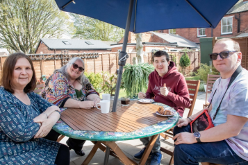 Four people sit around a garden table.
