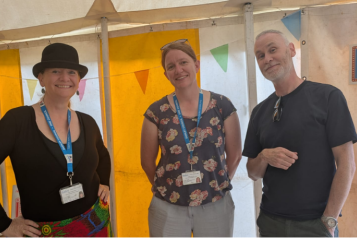 Three people stand in a tent and smile.
