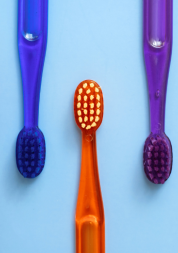 Five different coloured toothbrushes on a blue background.